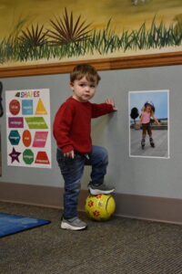 A child practices rolling a soccer ball.